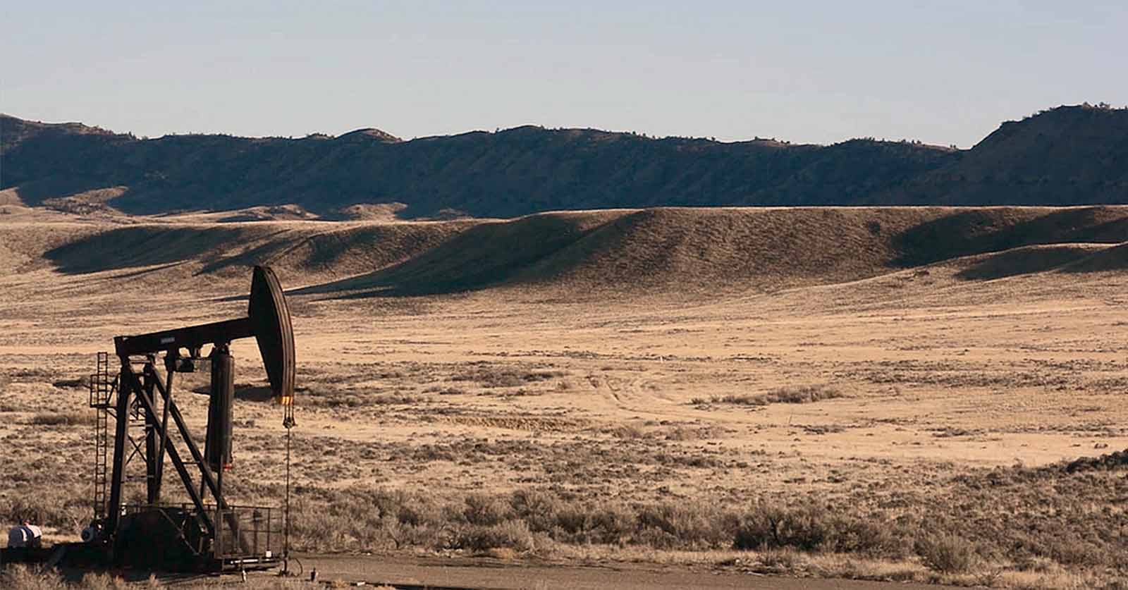 pumpjack in forground. Mountains in the background
