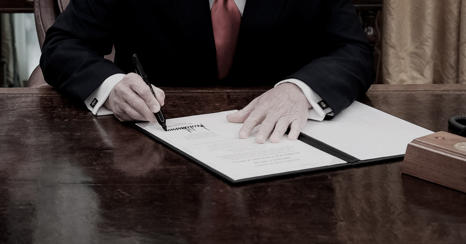 Image of Donald Trump signing a document