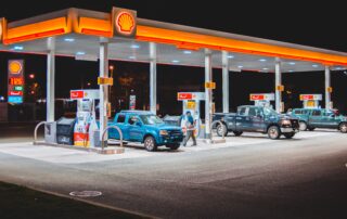 photo of a shell gas station at night with multiple vehicles at each pump