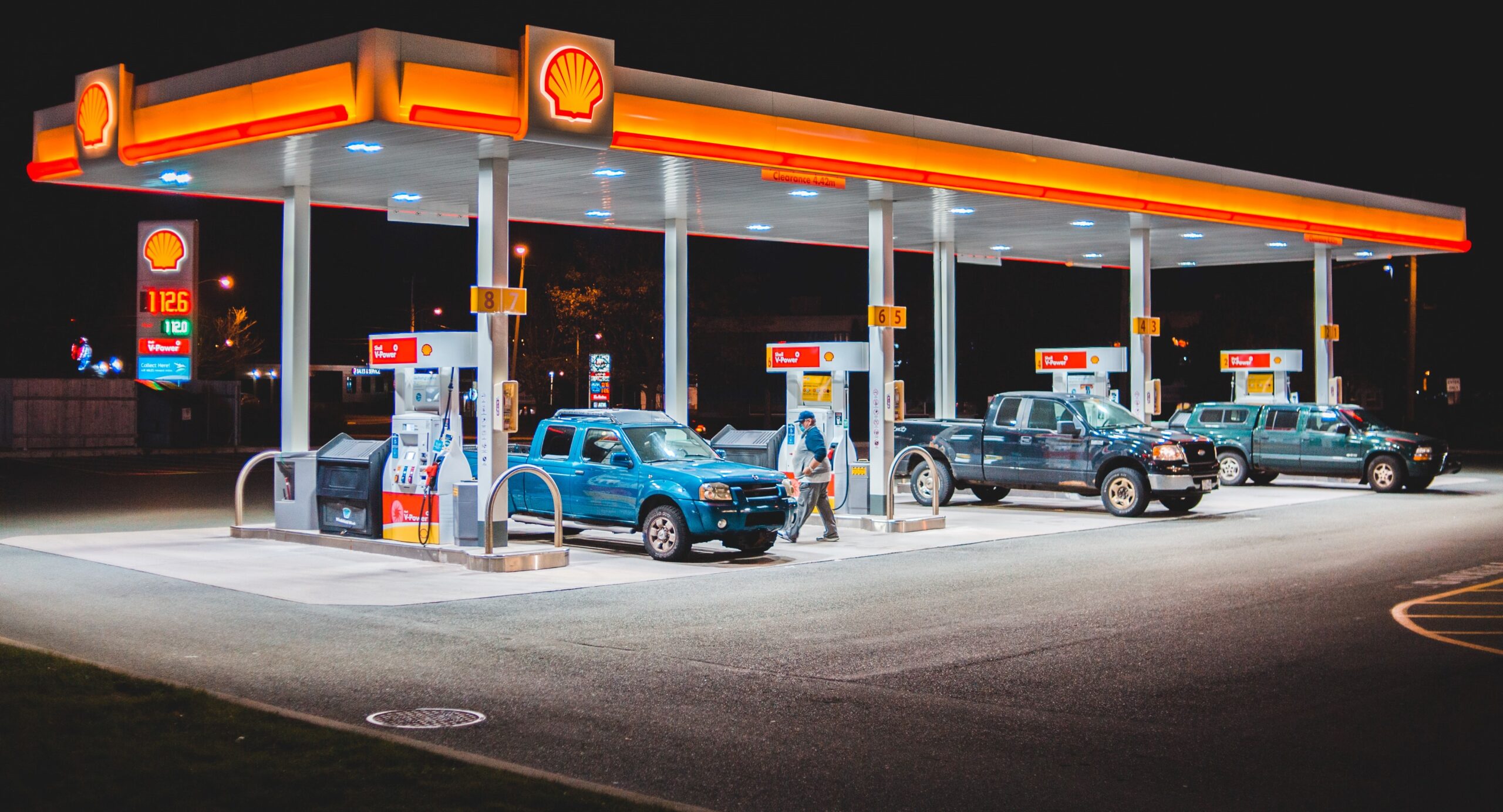 photo of a shell gas station at night with multiple vehicles at each pump
