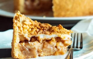 A slice of apple pie on a plate and a fork