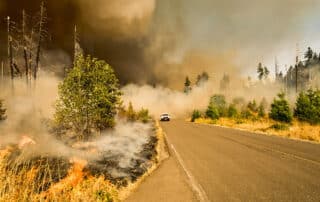 A pickup truck outfitted with a siren system drives between a wildfire