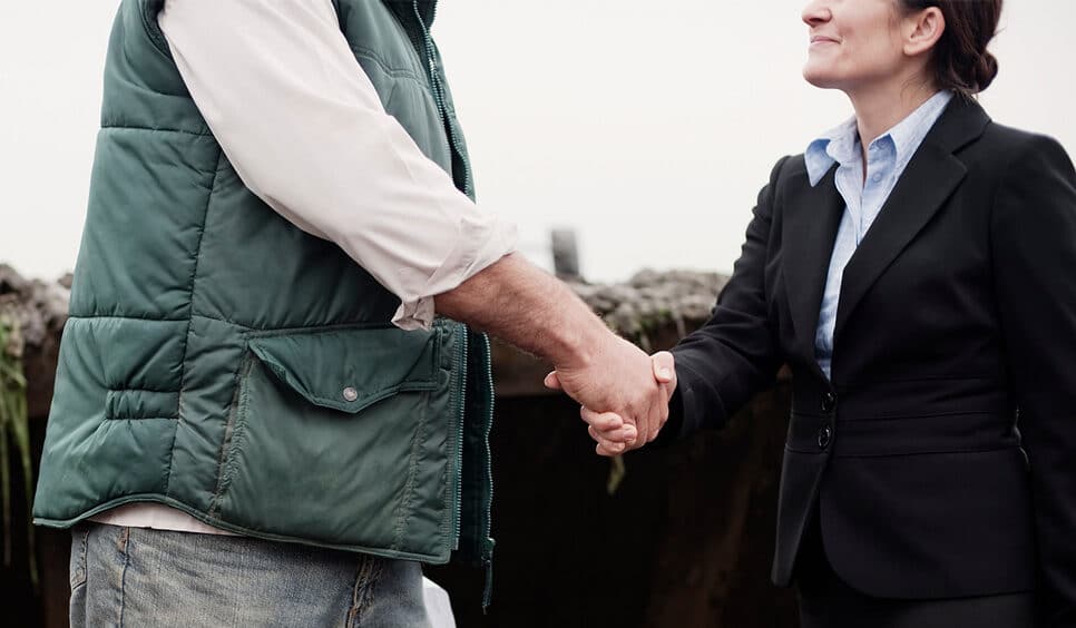 Farmer shaking hands with a suited woman