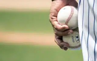 Baseball pitcher holding two baseballs in one hand