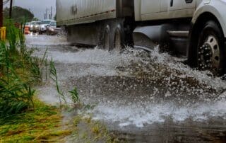 Truck splashing water offroad to avoid a flooded road with cars trailing behind