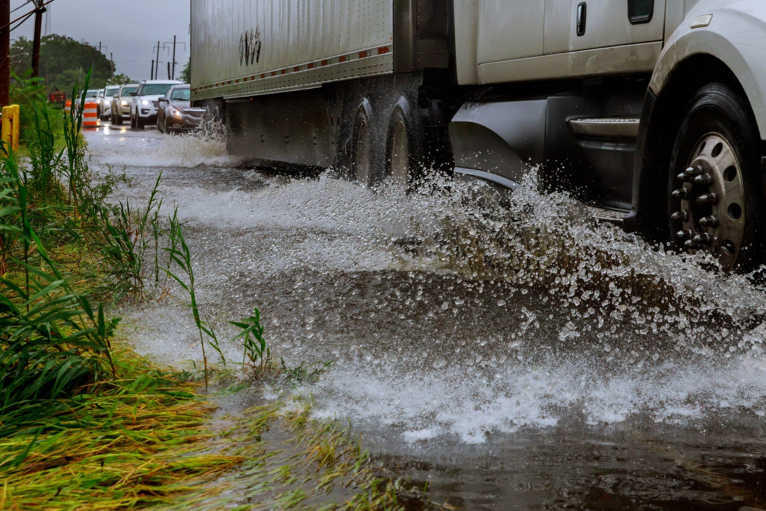 Truck splashing water offroad to avoid a flooded road with cars trailing behind