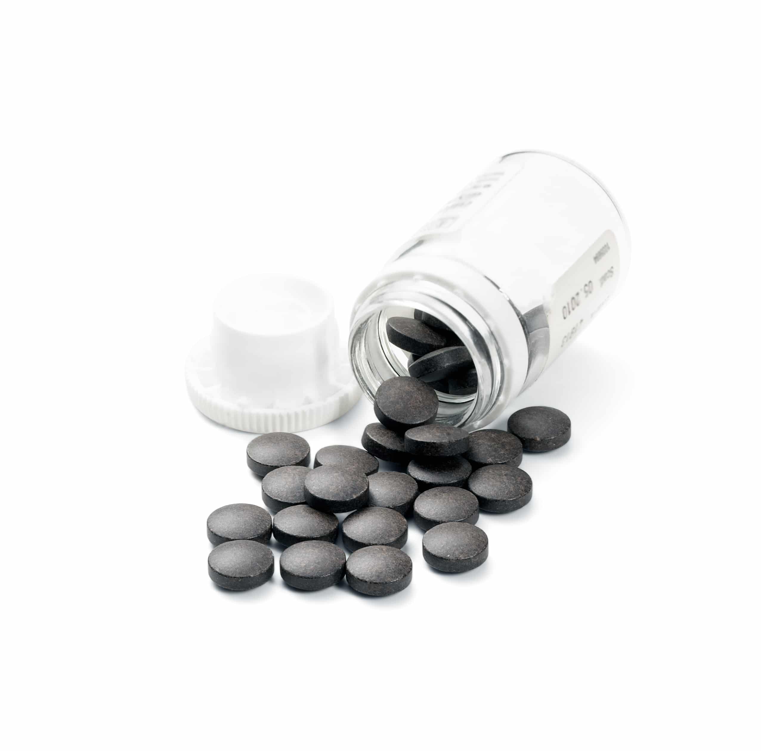black pills pouring out of transparent bottle