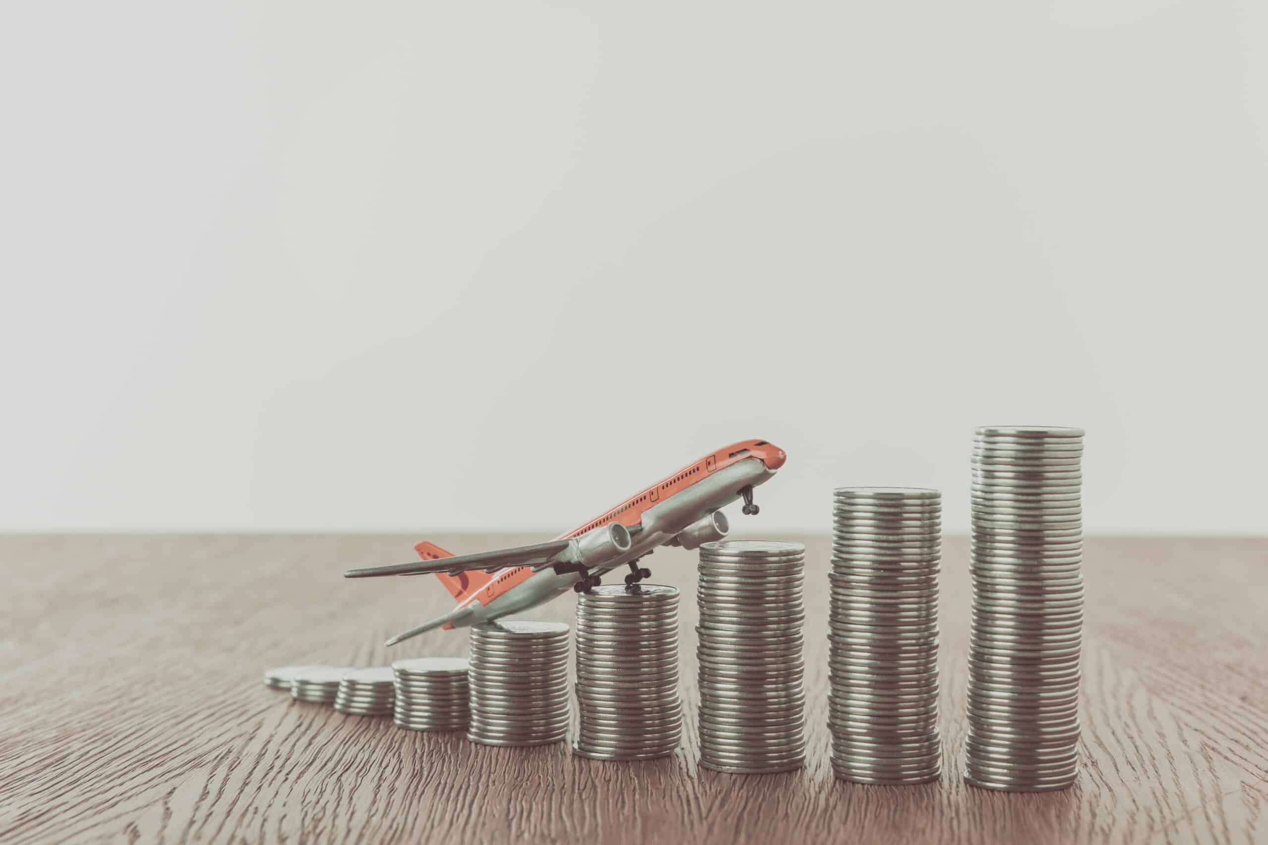 toy plane on stacks of coins on wooden table