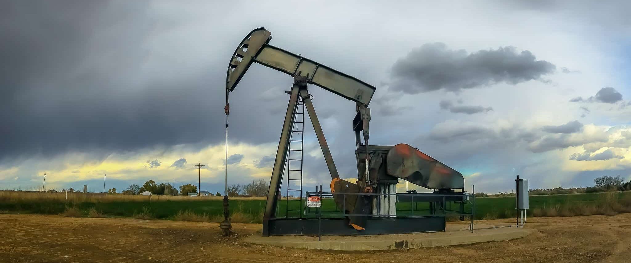 Oil Well in Colorado in foreground, moody grey sky in the background.