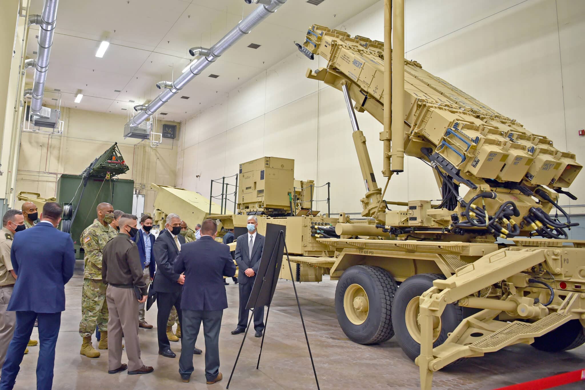 US Army Undersecretary and staff looking at a brown missile battery ina closed space