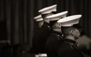 A sepia tone image of four U.S. Marines in "Dress Blues" standing in a line