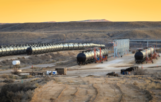 Oil tankers in Utah at a cargo railway depot with a yellow sunset sky in the foreground.