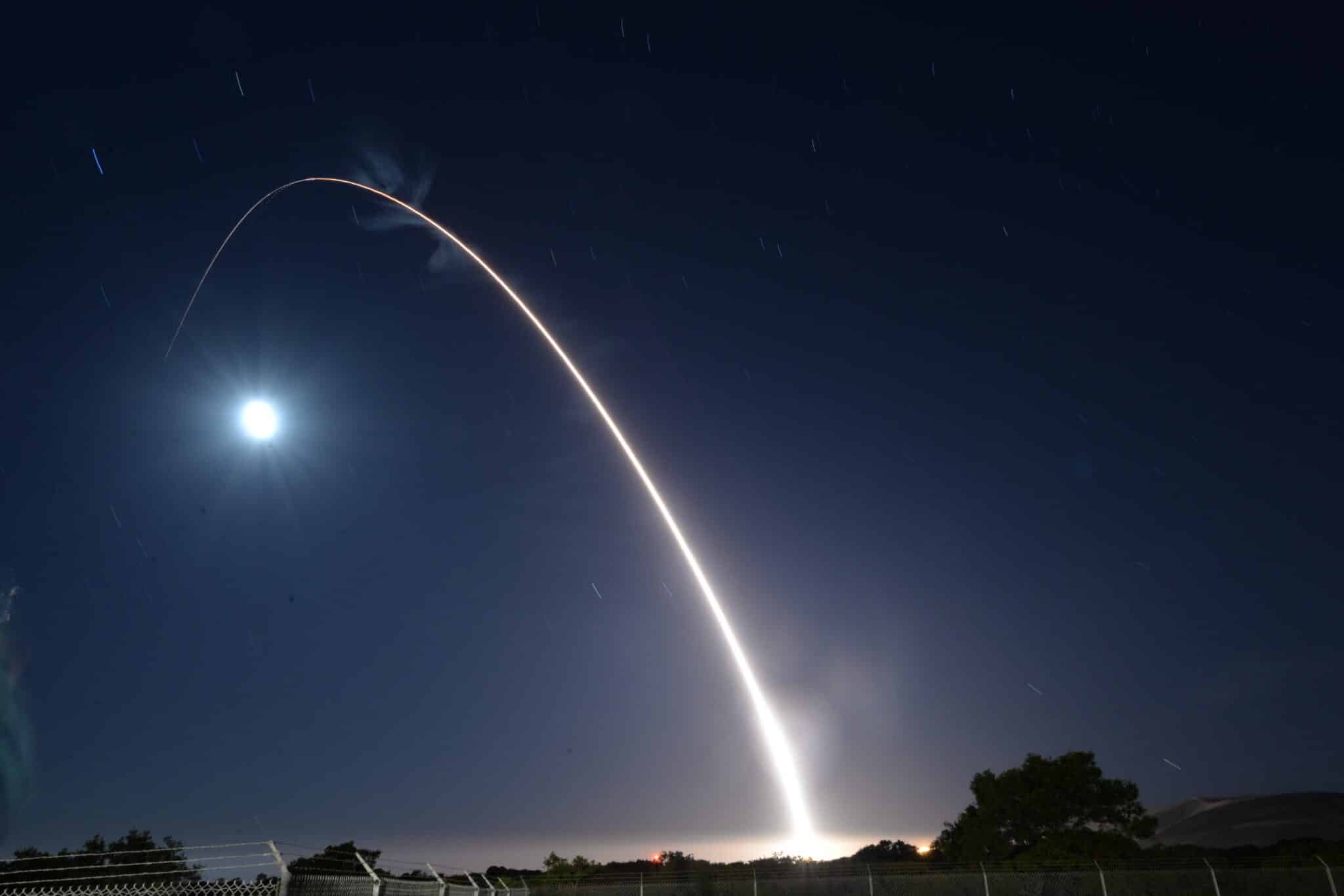 A Minuteman III ICBM missile launches at night with a bright white streak trailing it.