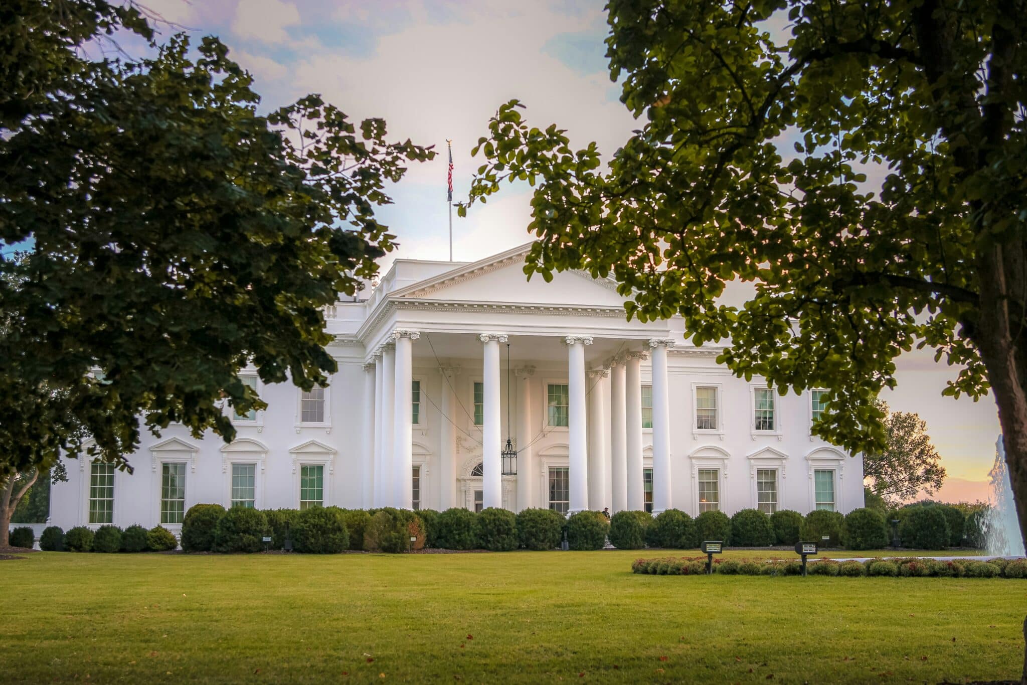 White house front facade at sunset with a vignette of foliage in the foreground