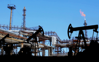 oil refinery expelling methane in the background with oil pumpjacks at work in the foreground.