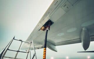 Aircraft fueling hose attached to the wing of a parked airplane