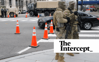 Two National Guardsmen supervise a DC checkpoint as a sedan is cleared to pass