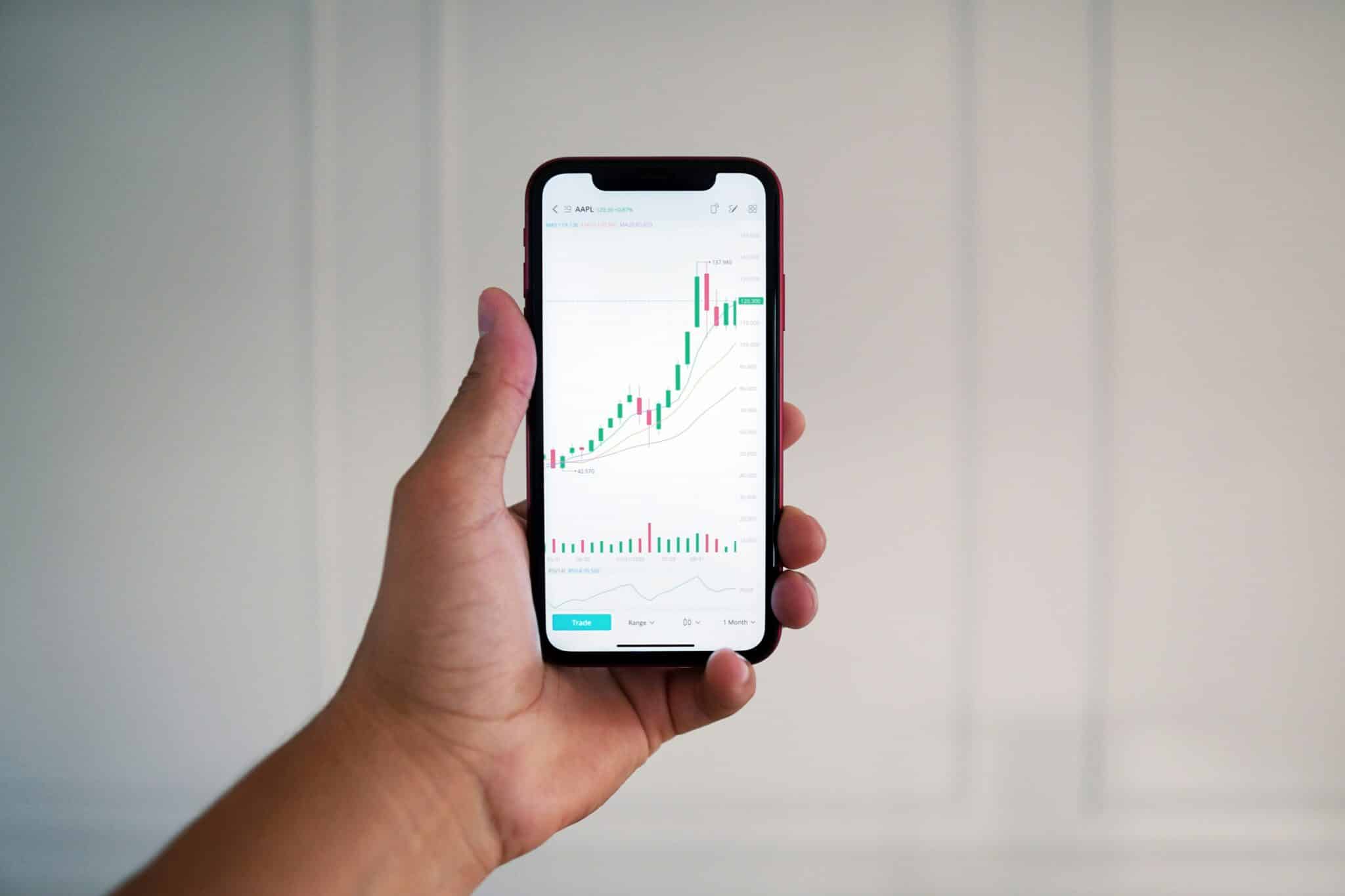 person holding black smartphone with a stock market graph on the screen