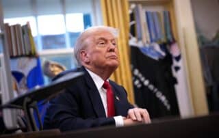 Donald Trump sits in the Oval Office listening attentively