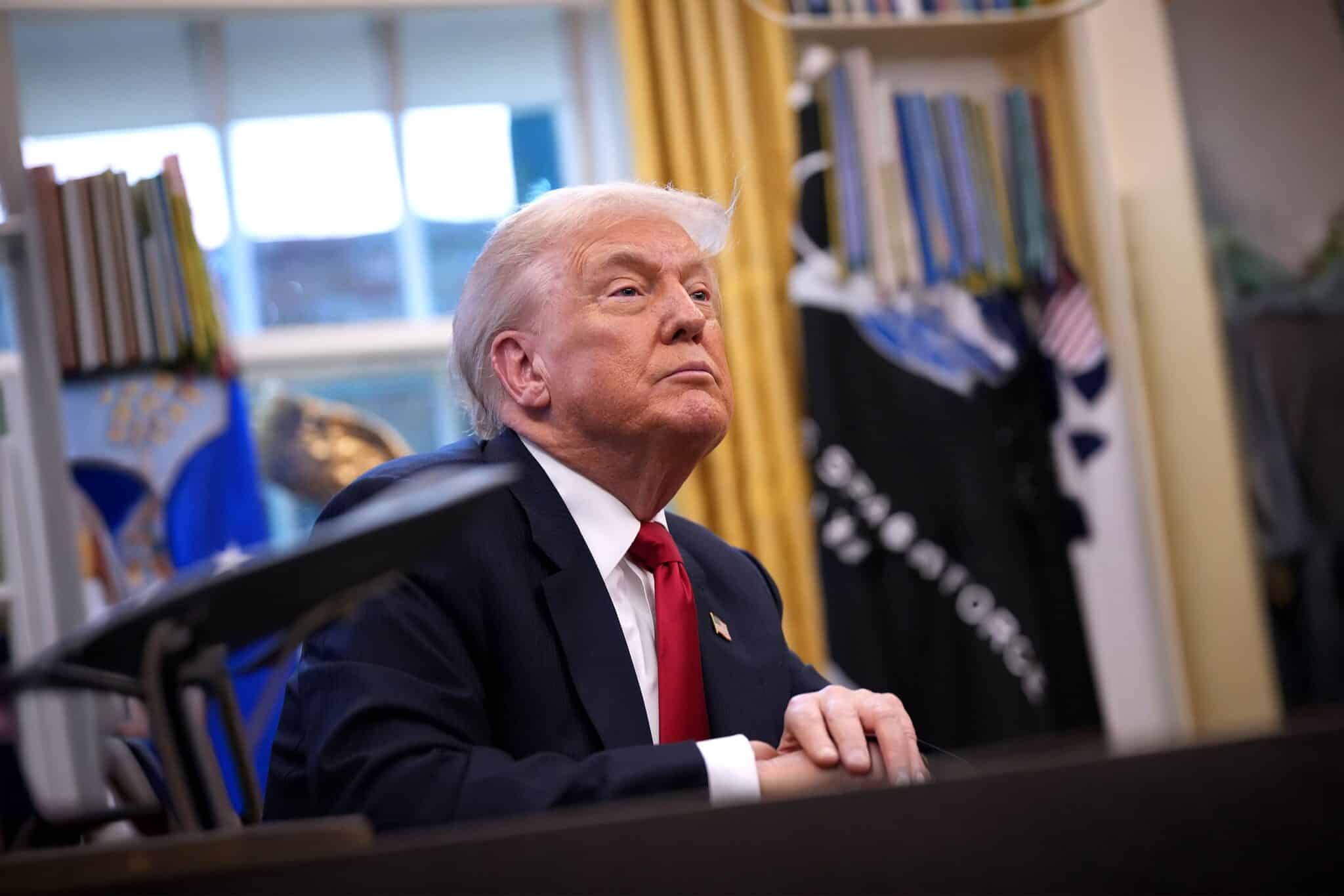 Donald Trump sits in the Oval Office listening attentively