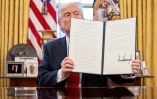 President Trump holds up a signed document in the oval office