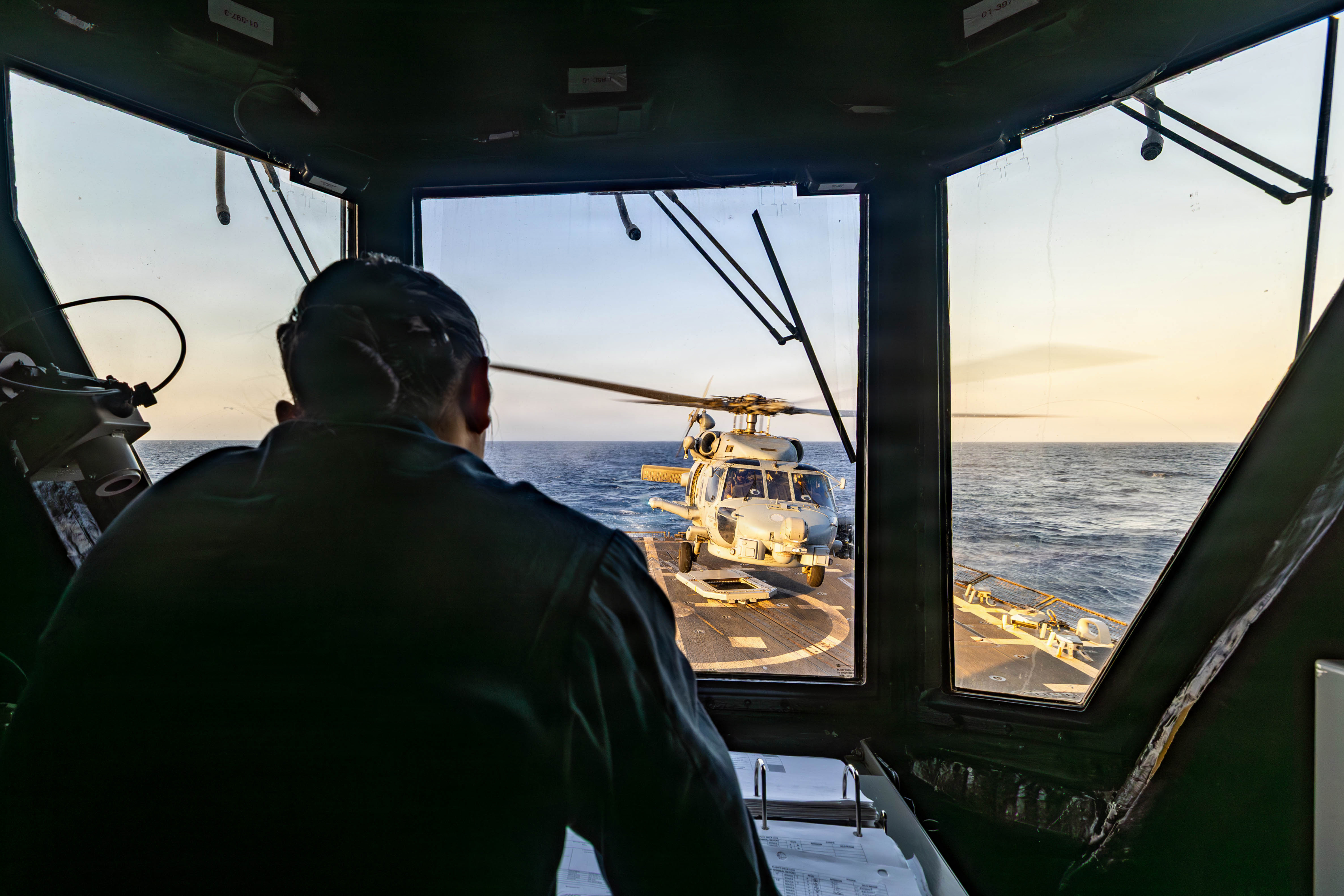 A U.S. Sailor observes as an MH-60R Sea Hawk, assigned to Helicopter Maritime Strike Squadron (HSM) 51, landing on the flight deck of Arleigh Burke-class guided-missile destroyer USS Rafael Peralta (DDG 115), as it patrols the Arabian Sea enforcing a maritime blockade against ships entering or exiting Iranian ports and coastal areas, May 12, 2026. Rafael Peralta is deployed to the U.S. 5th Fleet area of operations to support maritime security and stability in the Middle East. (U.S. Navy photo)