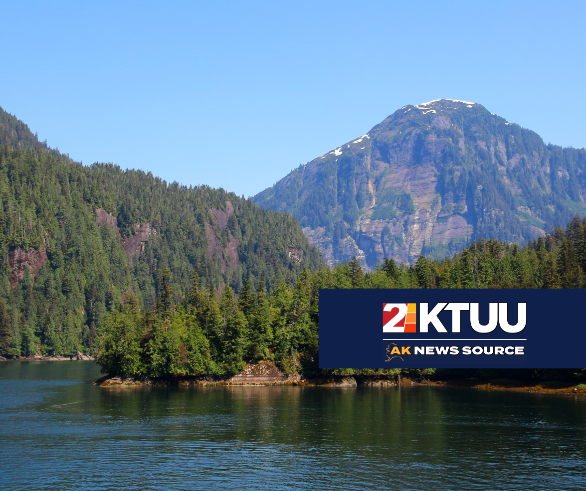 a breathtaking view of Misty Fjords with a big river in the foreground and wooded mountains in the back.