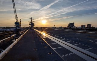 image of an aircraft carrier deck with the lowered sun in the background