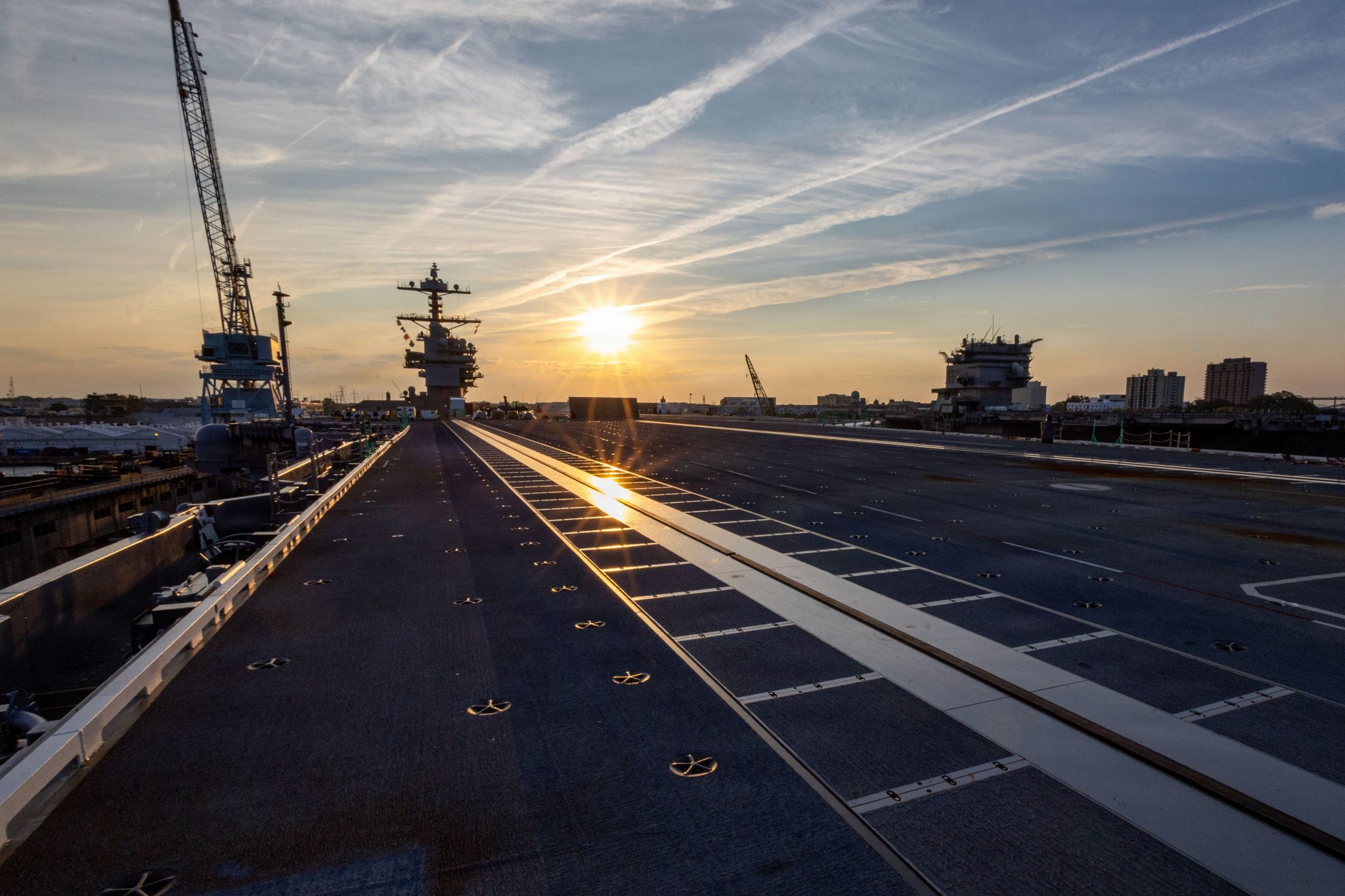 image of an aircraft carrier deck with the lowered sun in the background